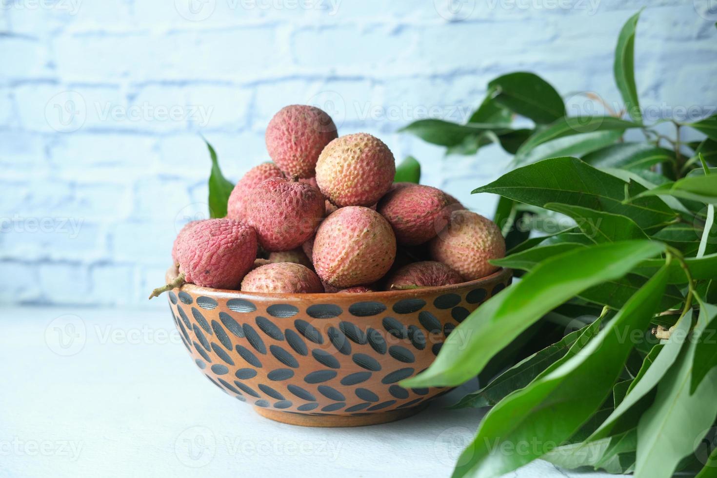 litchi i en skål på en träbakgrund foto