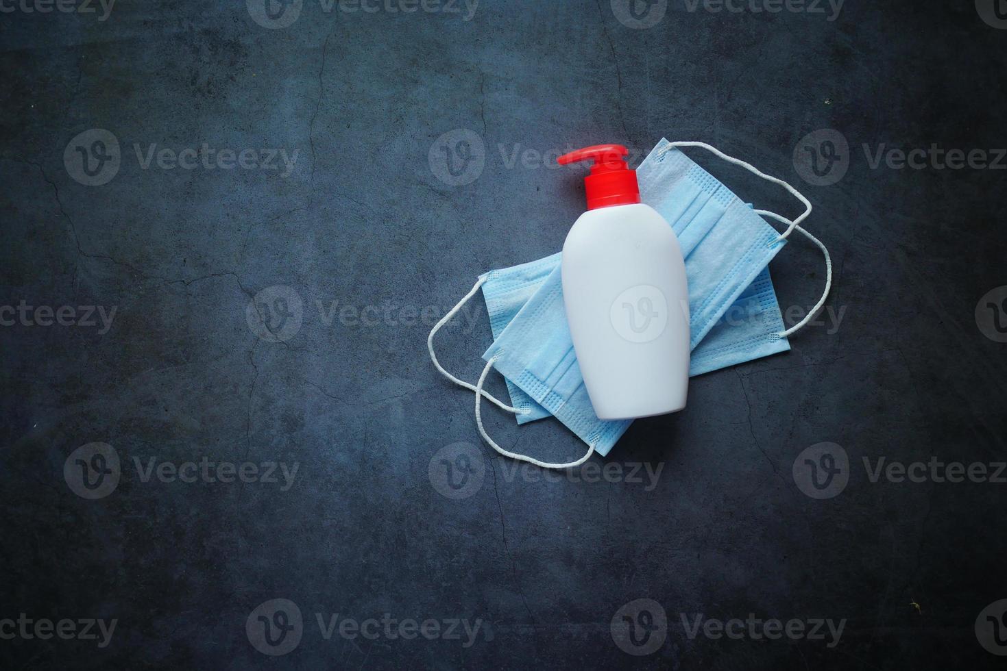 kirurgiska masker och handtvätt i en behållare på svart bakgrund foto