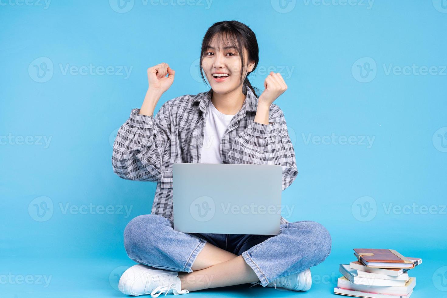 asiatisk kvinnlig student med lekfullt uttryck på blå bakgrund foto