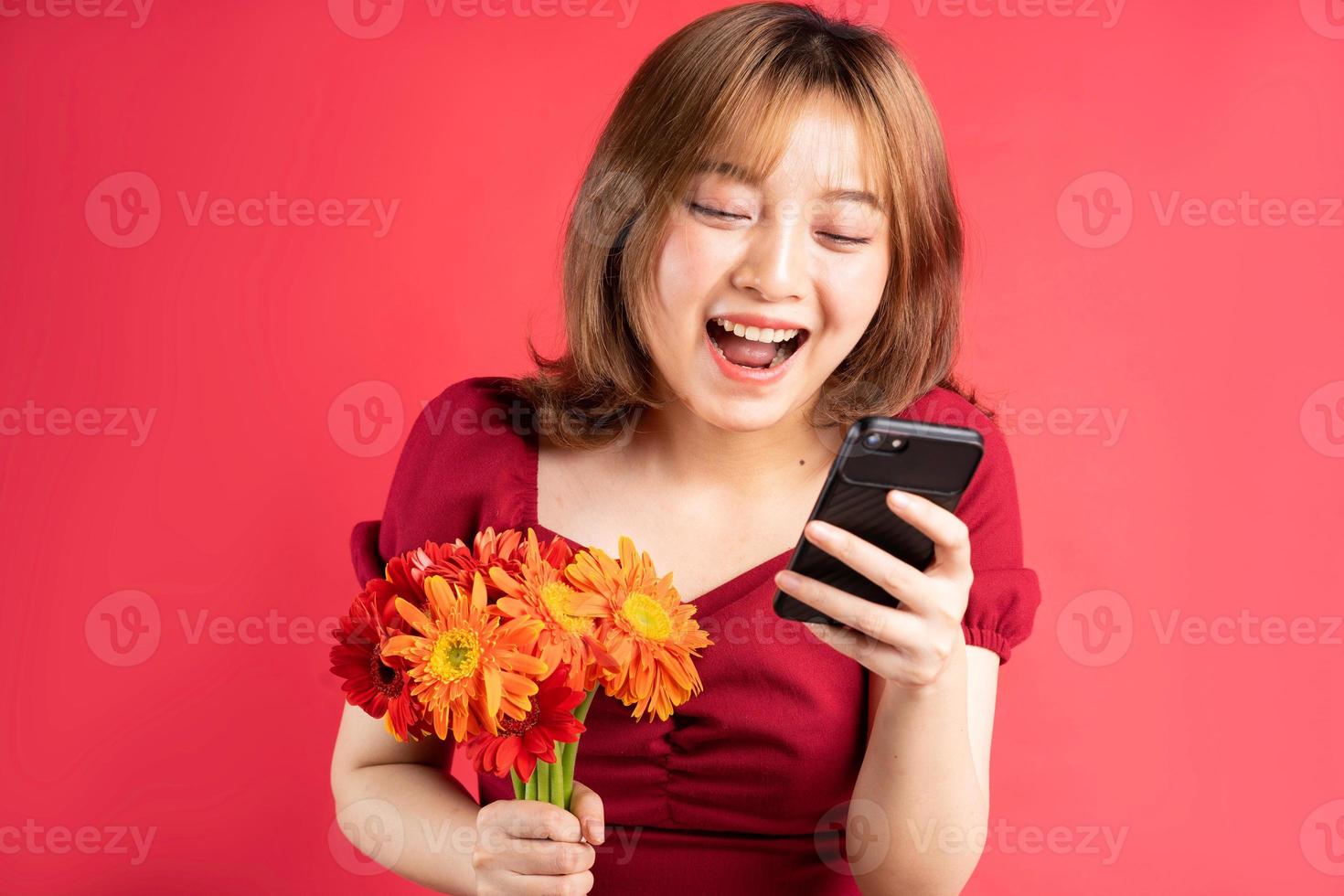 ung flicka håller blommor och använder telefon med glada uttryck på bakgrunden foto