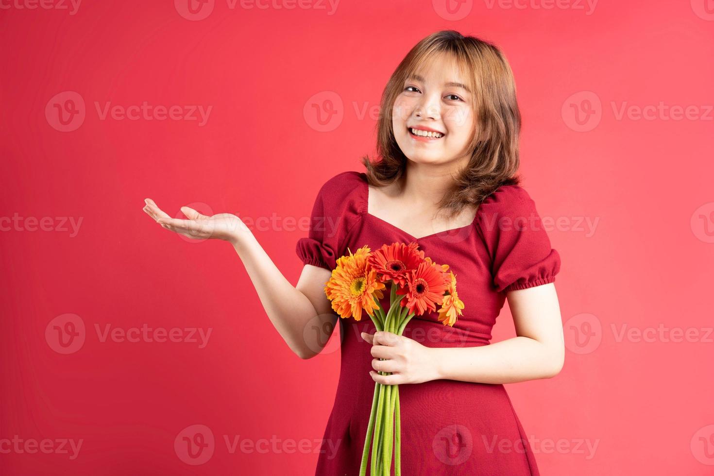 ung flicka håller bukett gerberor med glada uttryck på bakgrunden foto