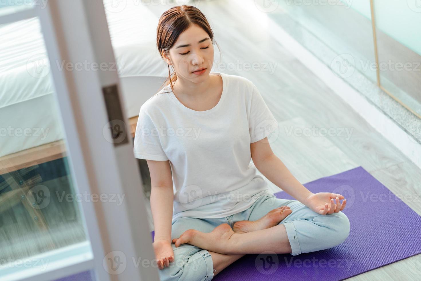 vacker asiatisk kvinna som övar meditation hemma foto