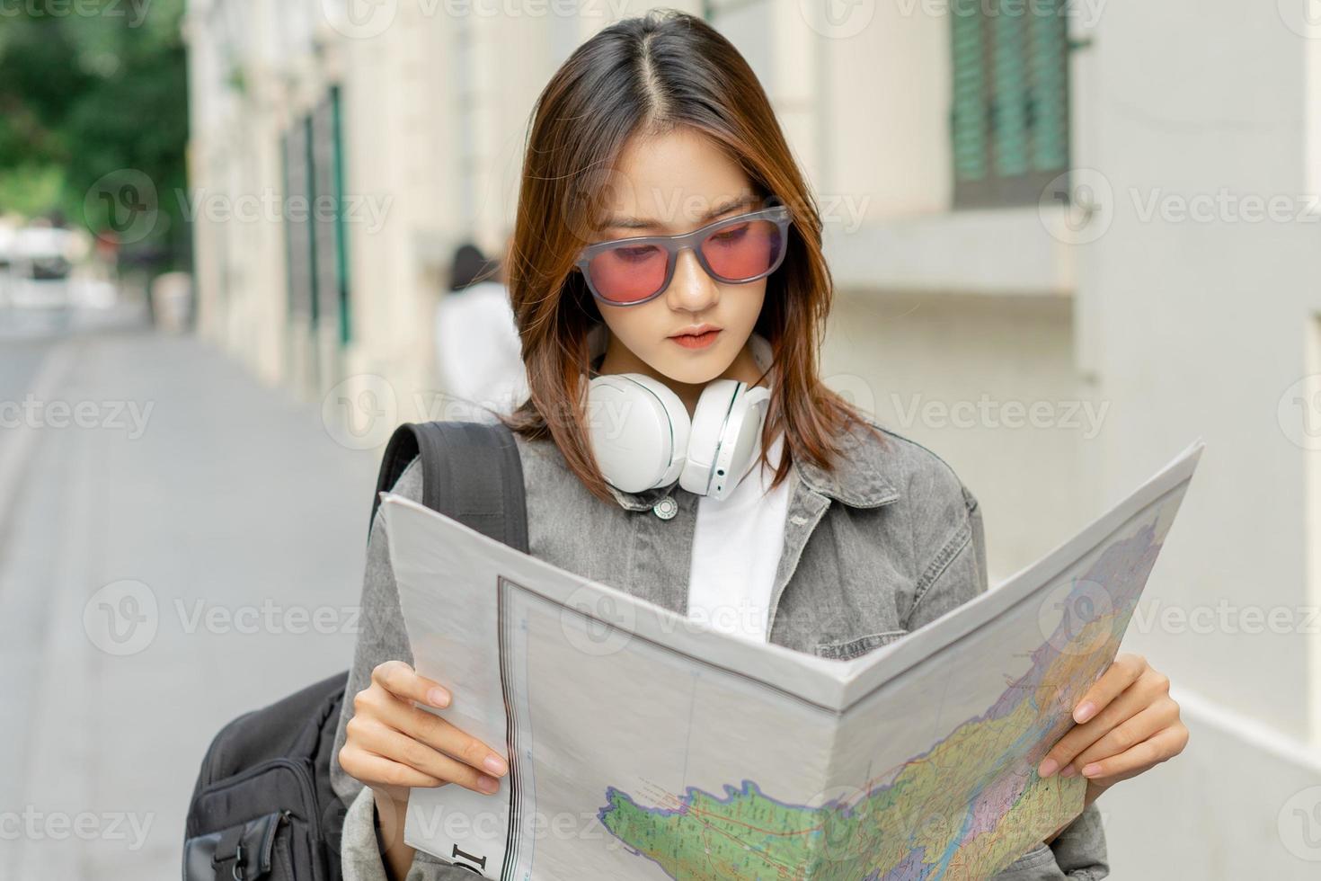 asiatisk kvinnlig turist läser kartan för att hitta sin väg foto
