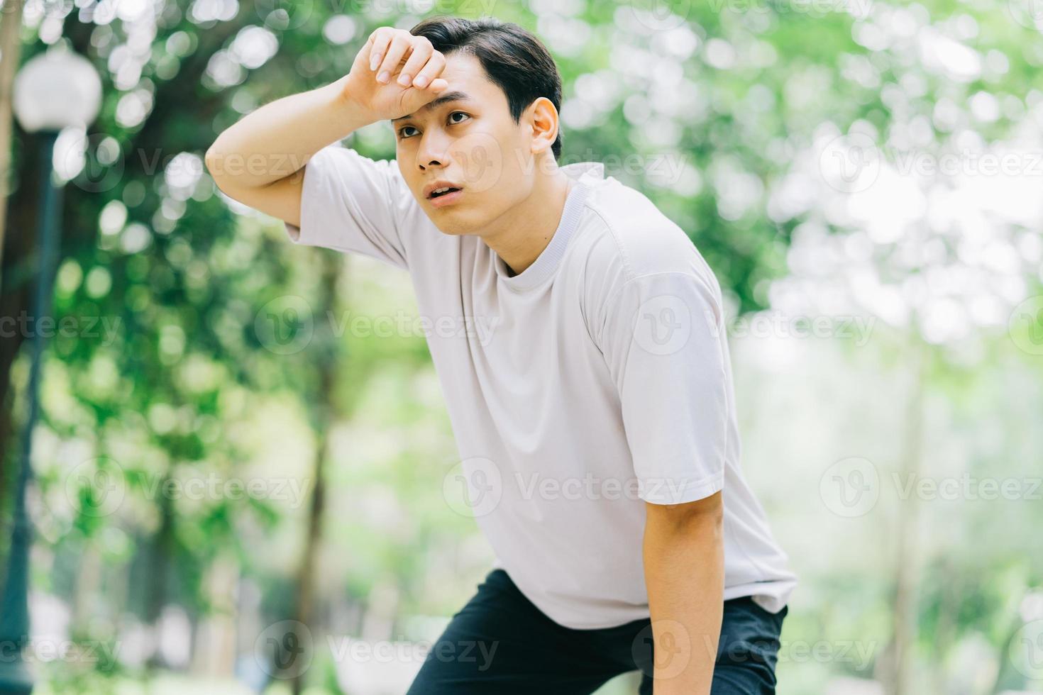 asiatisk man som vilar efter jogging i park foto