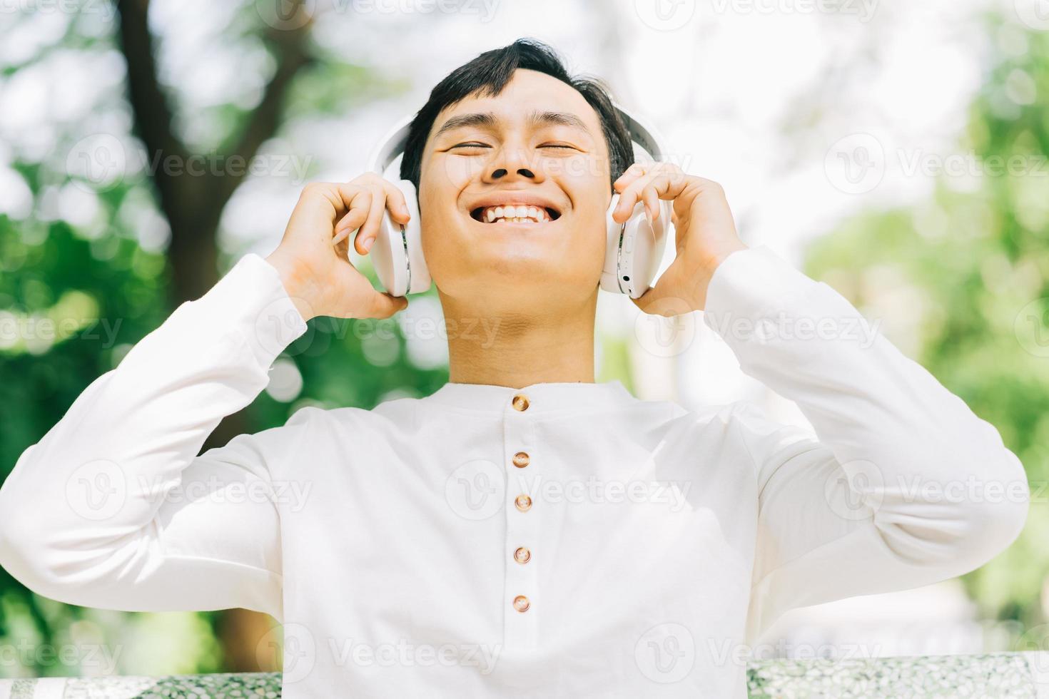 stilig asiatisk man som njuter av musik i parken foto