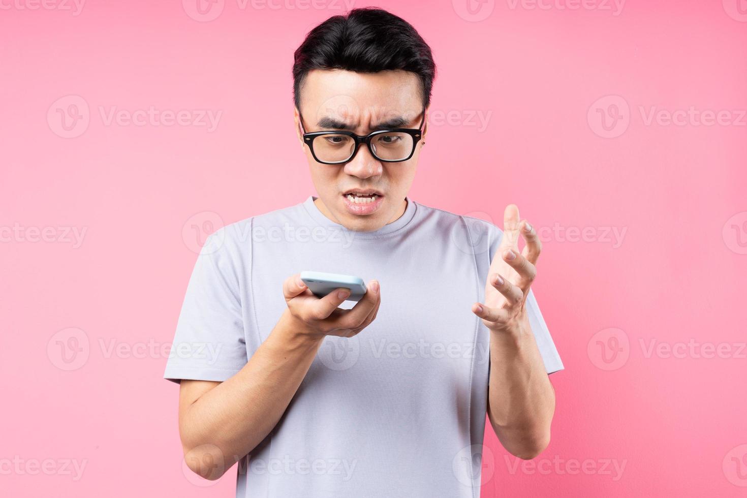 porträtt av asiatisk man med smartphone på rosa bakgrund foto