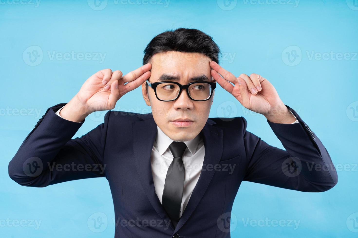 asiatisk affärsman som tänker på arbete på blå bakgrund foto
