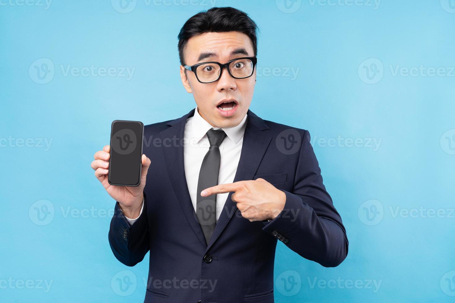 asiatisk affärsman bär kostym innehav smartphone på blå bakgrund foto