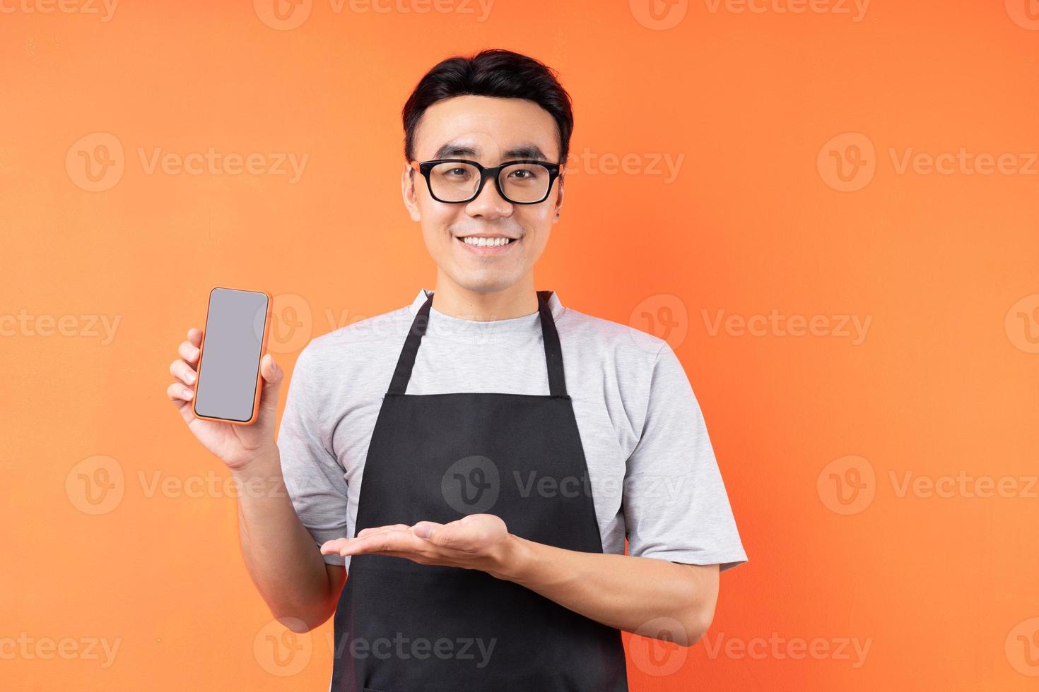 porträtt av asiatisk manlig servitör som poserar på orange bakgrund foto