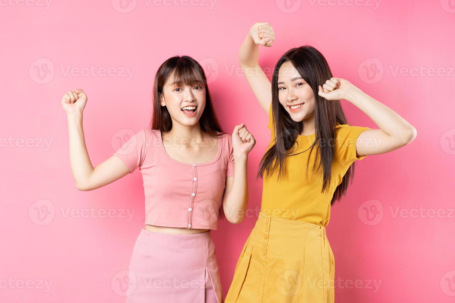 porträtt av två vackra unga asiatiska flickor som poserar på rosa bakgrund foto