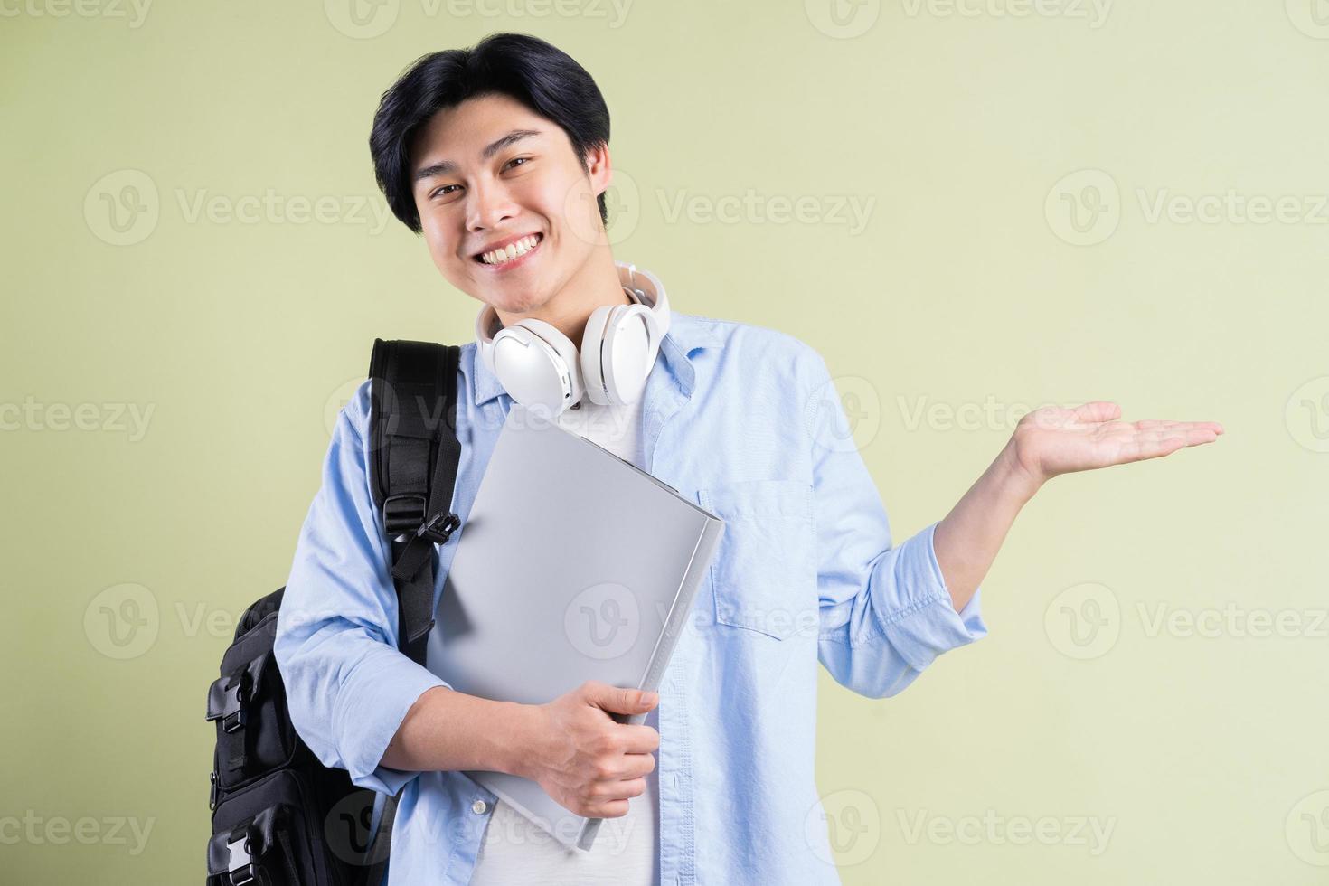 manlig asiatisk student som håller handen till vänster foto