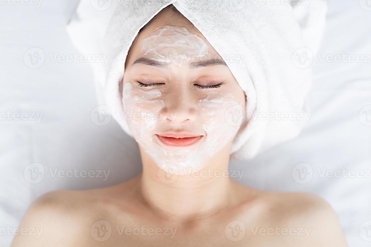 asiatisk kvinna som gör skönhetsbehandlingar, spabehandlingar och appliceras kräm i ansiktet foto