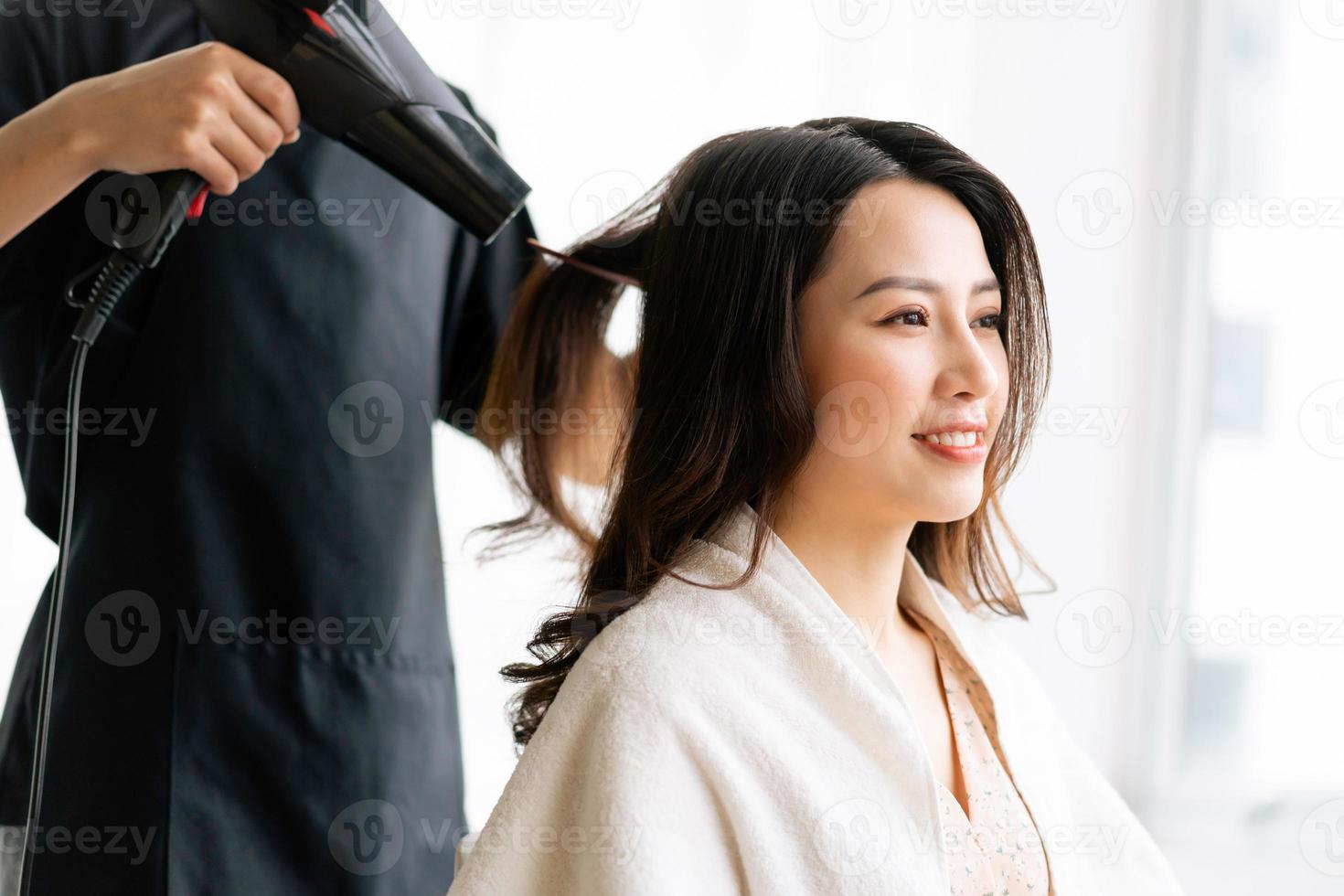 asiatisk kvinna med lyckligt uttryck gör frisör på salong foto