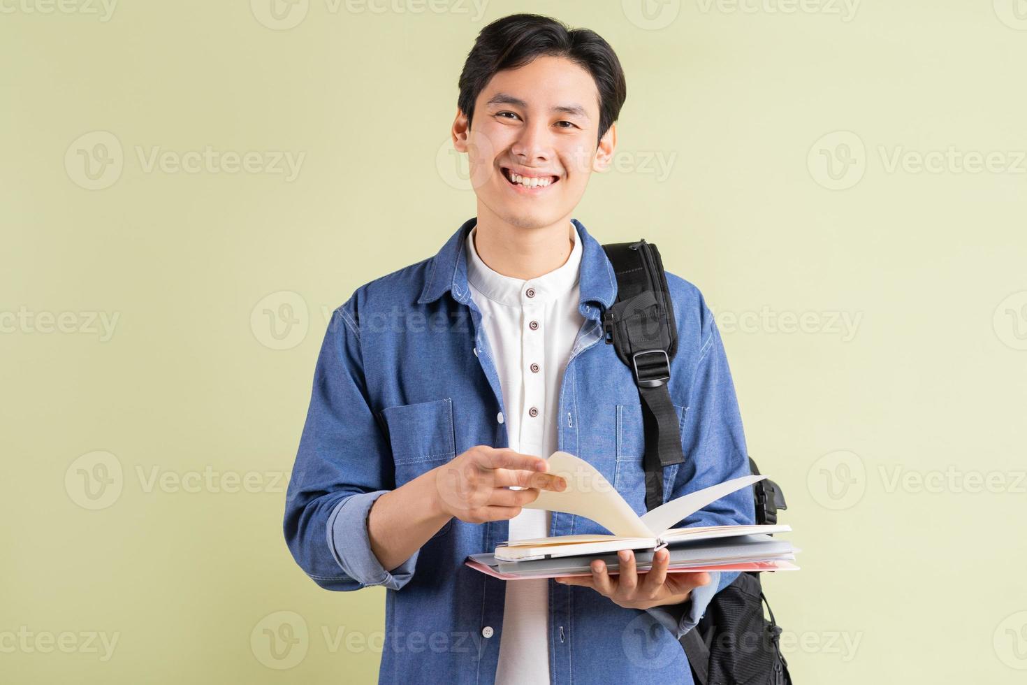 foto av stilig asiatisk student som ler och håller boken i handen