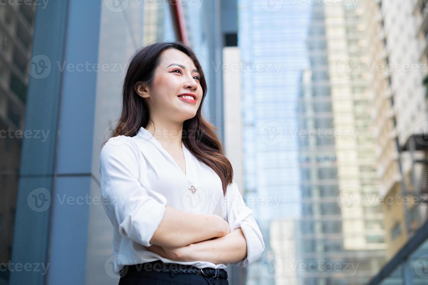 ung asiatisk kvinna stod med armarna korsade med ett självsäkert blick foto