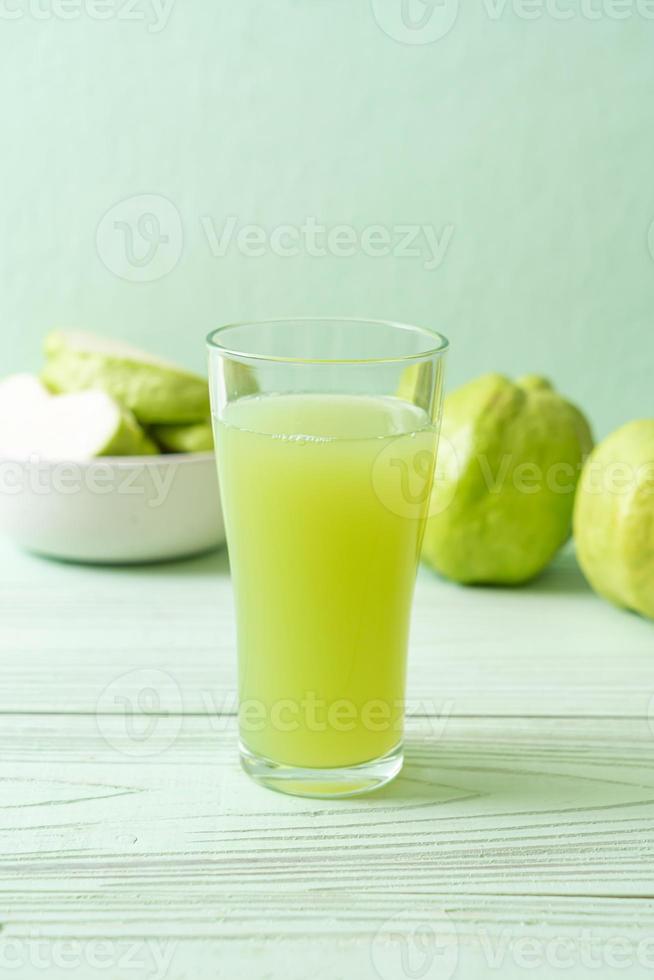 färskt guavajuiceglas med färsk guavafrukt på träbord foto
