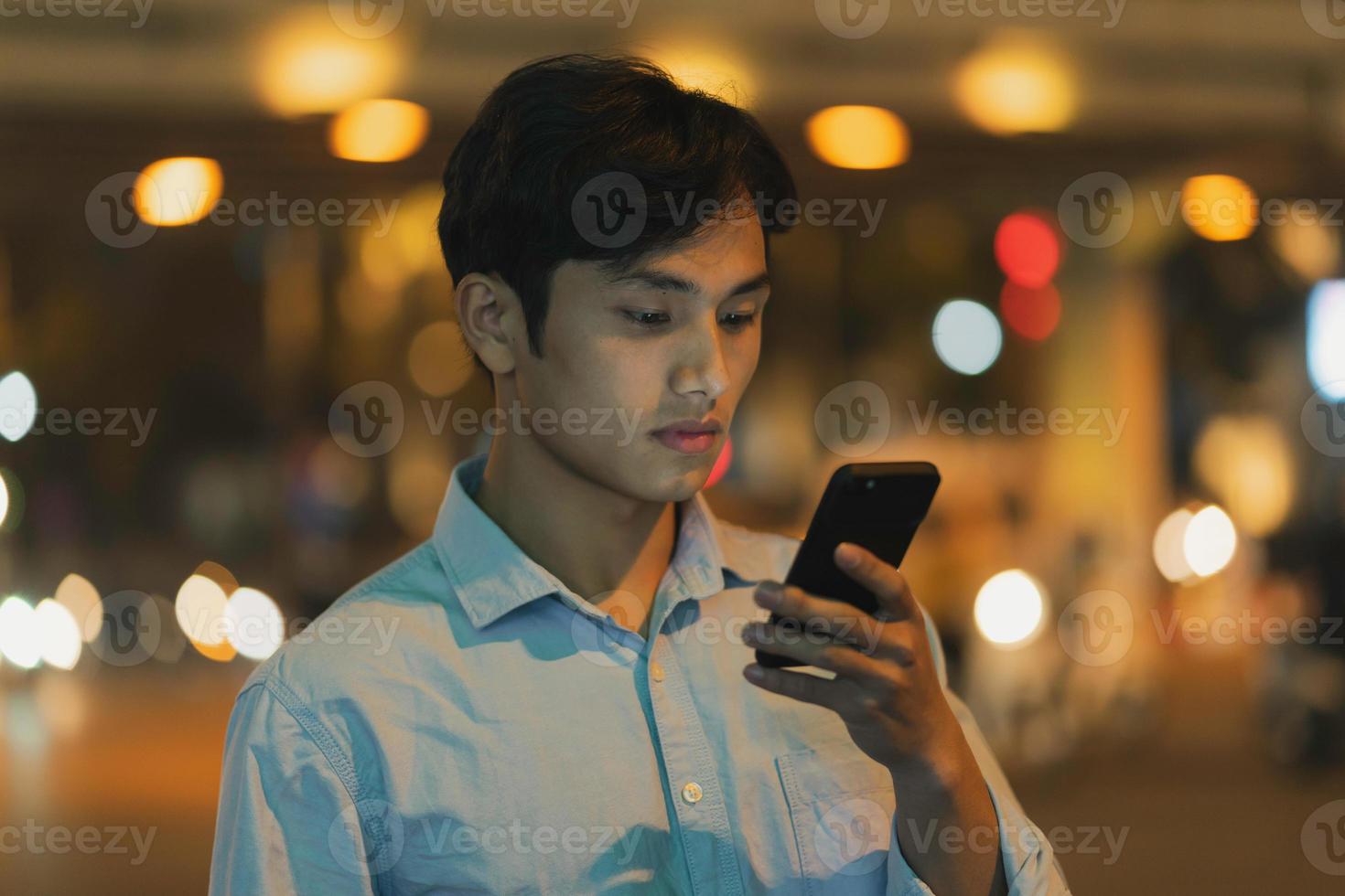 mannen står med en mobiltelefon på himlen på kvällen foto