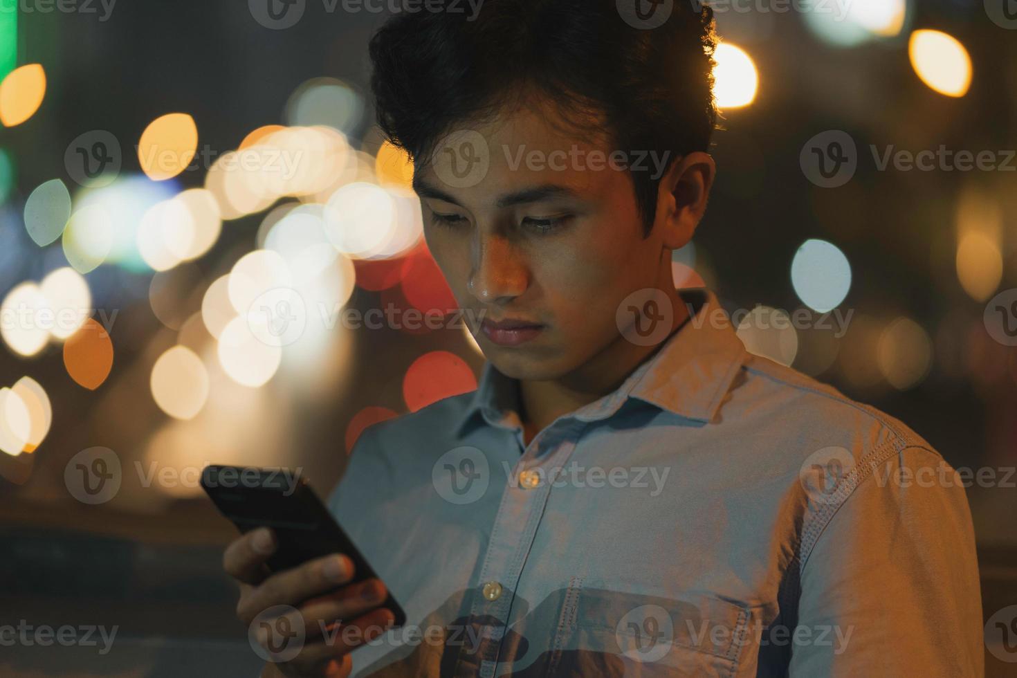 mannen står med en mobiltelefon på himlen på kvällen foto