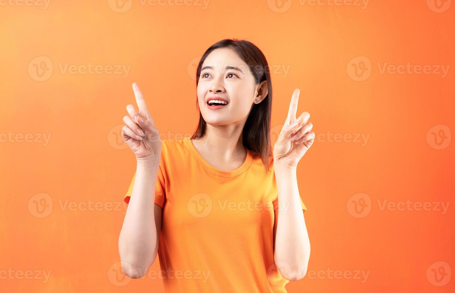 bild av ung asiatisk kvinna som bär orange t-shirt på orange bakgrund foto