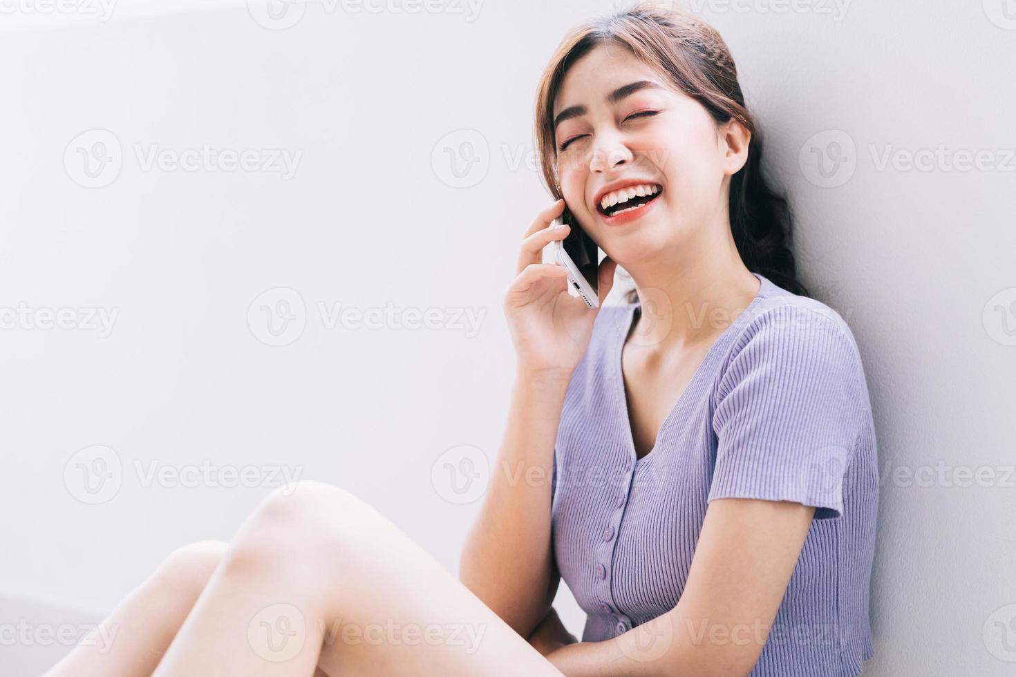 vacker ung asiatisk kvinna som använder smarttelefonen hemma foto