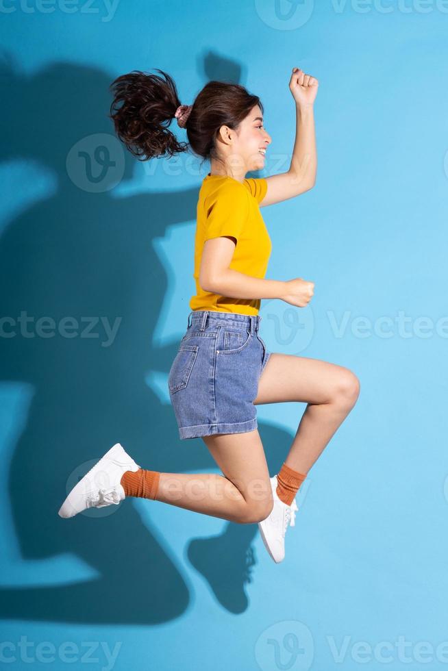 ung asiatisk flicka som poserar på blå bakgrund foto