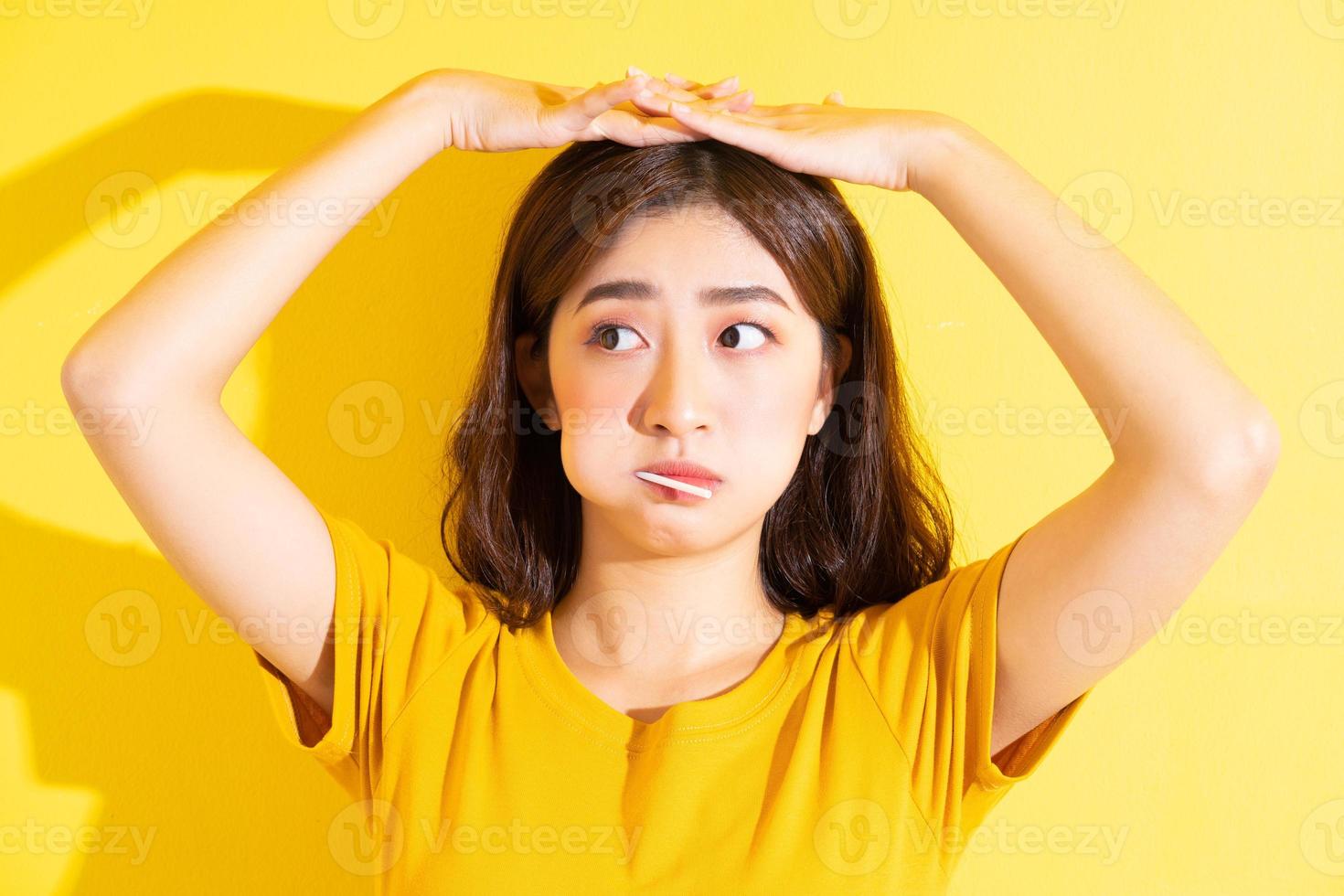 ung asiatisk kvinna som äter klubba på gul bakgrund foto