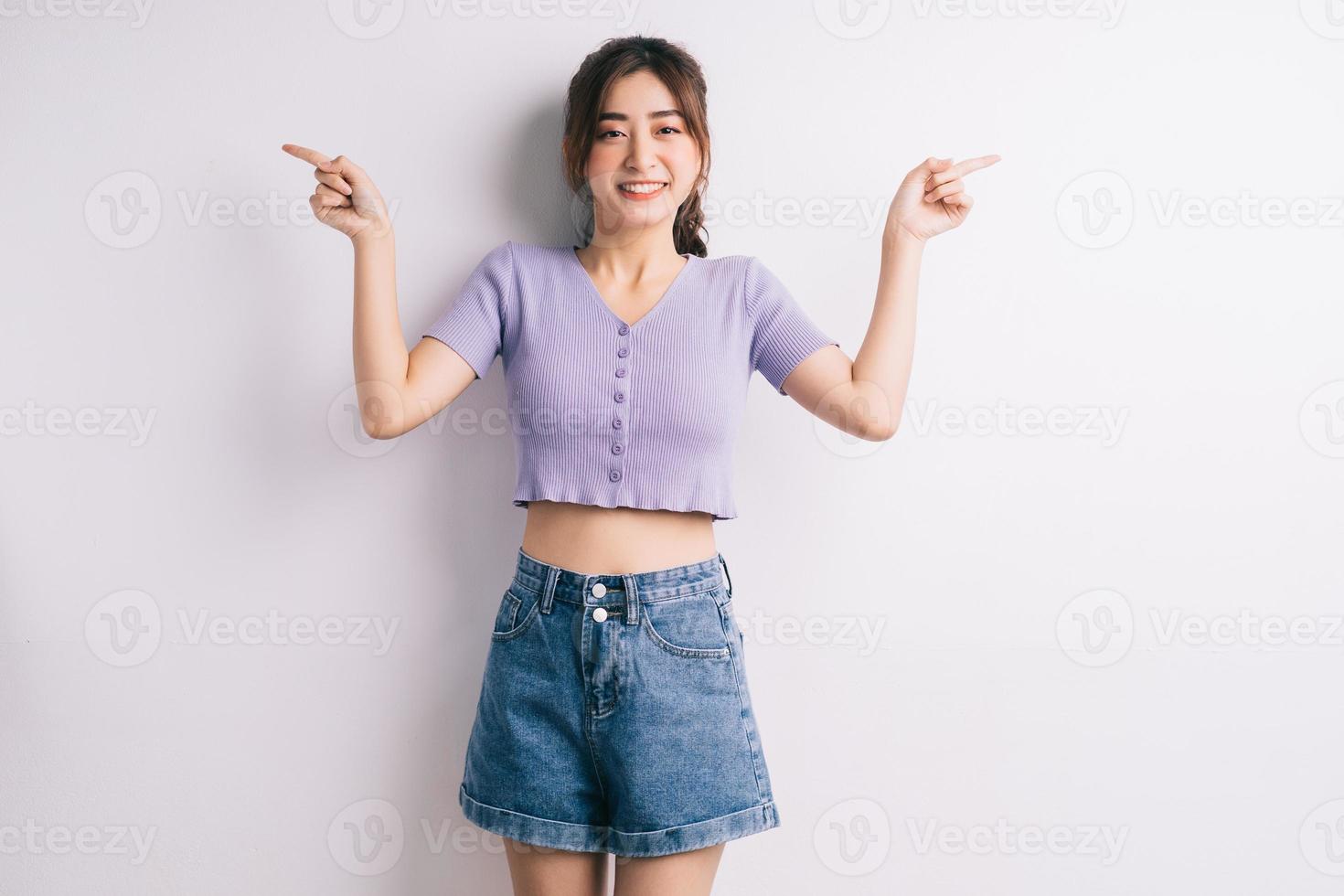 glad ung asiatisk tjej som pekar på vit bakgrund foto