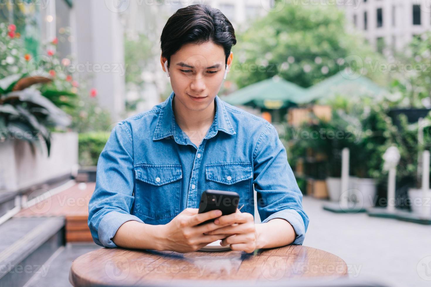 ung asiatisk man som använder smartphonen på kaféet foto