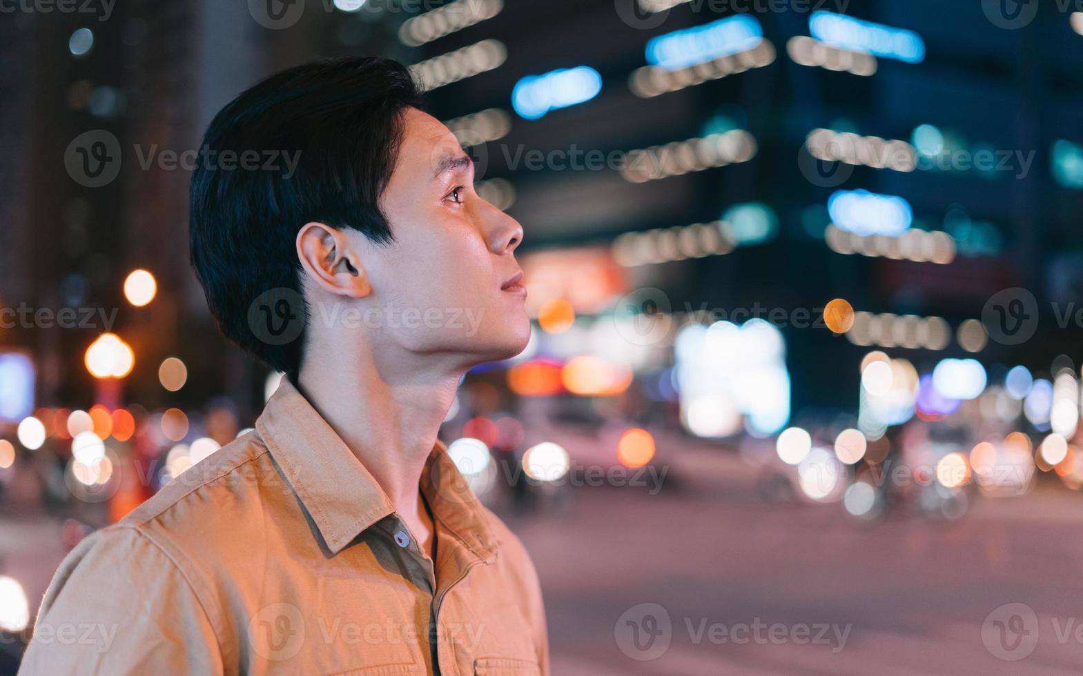 asiatisk man går på gatan på natten och känner sig förlorad foto