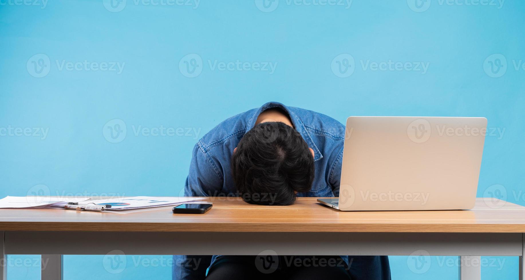 asiatisk affärsman tappade huvudet på bordet på grund av trycket på jobbet foto