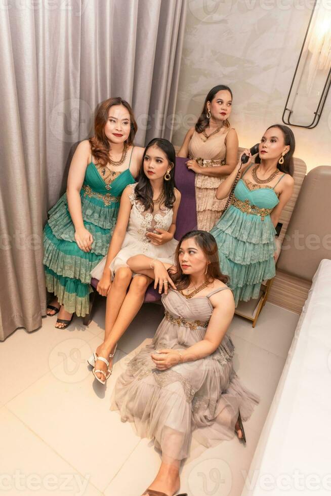 en grupp av asiatisk kvinnor i glamorös och lyxig kläder är Sammanträde på de soffa med deras vänner efter festa foto