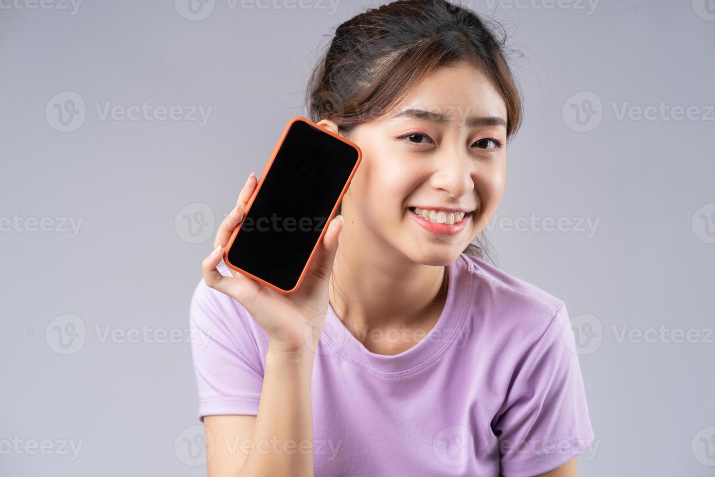 ung asiatisk kvinna som visar smarttelefons blank skärm foto