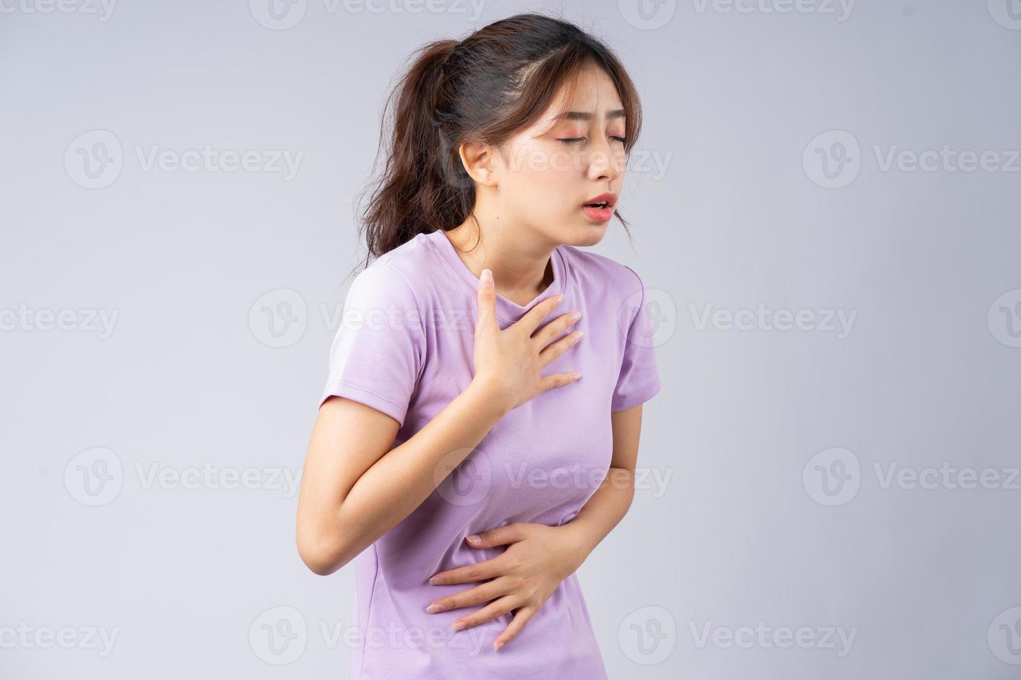 ung asiatisk kvinna som lider av gastroesofageal refluxsjukdom foto