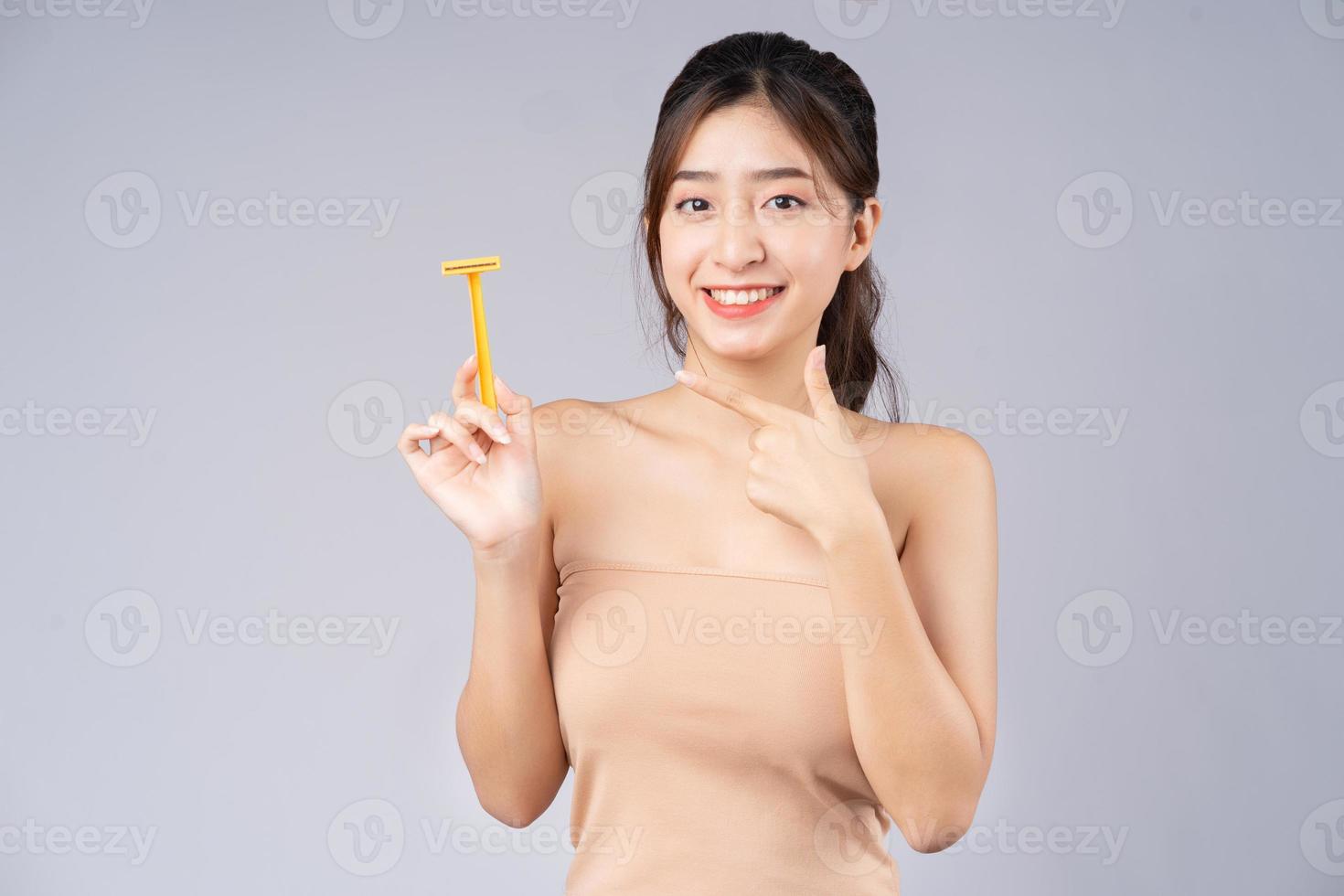 ung asiatisk tjej använder en rakhyvel för att ta bort hår foto