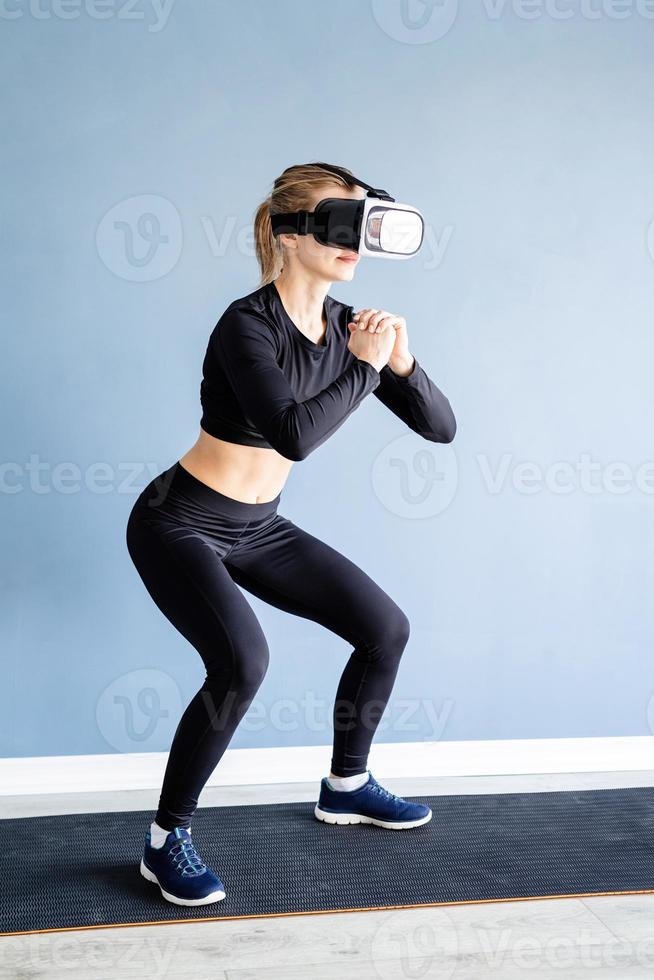 ung blond kvinna som bär virtual reality-glasögon som hukar hemma foto