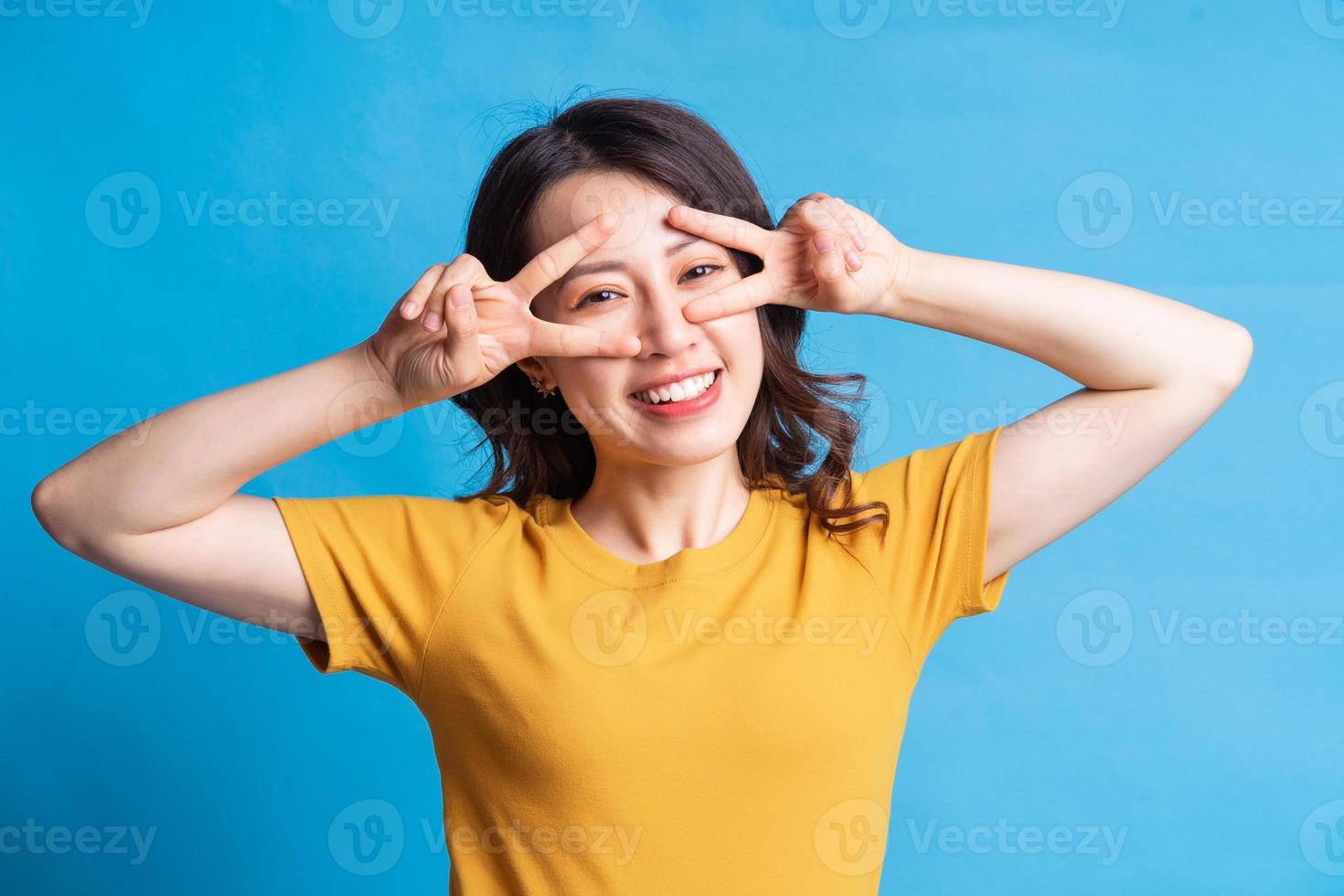den vackra asiatiska kvinnan bildar en fredsymbol med handen foto
