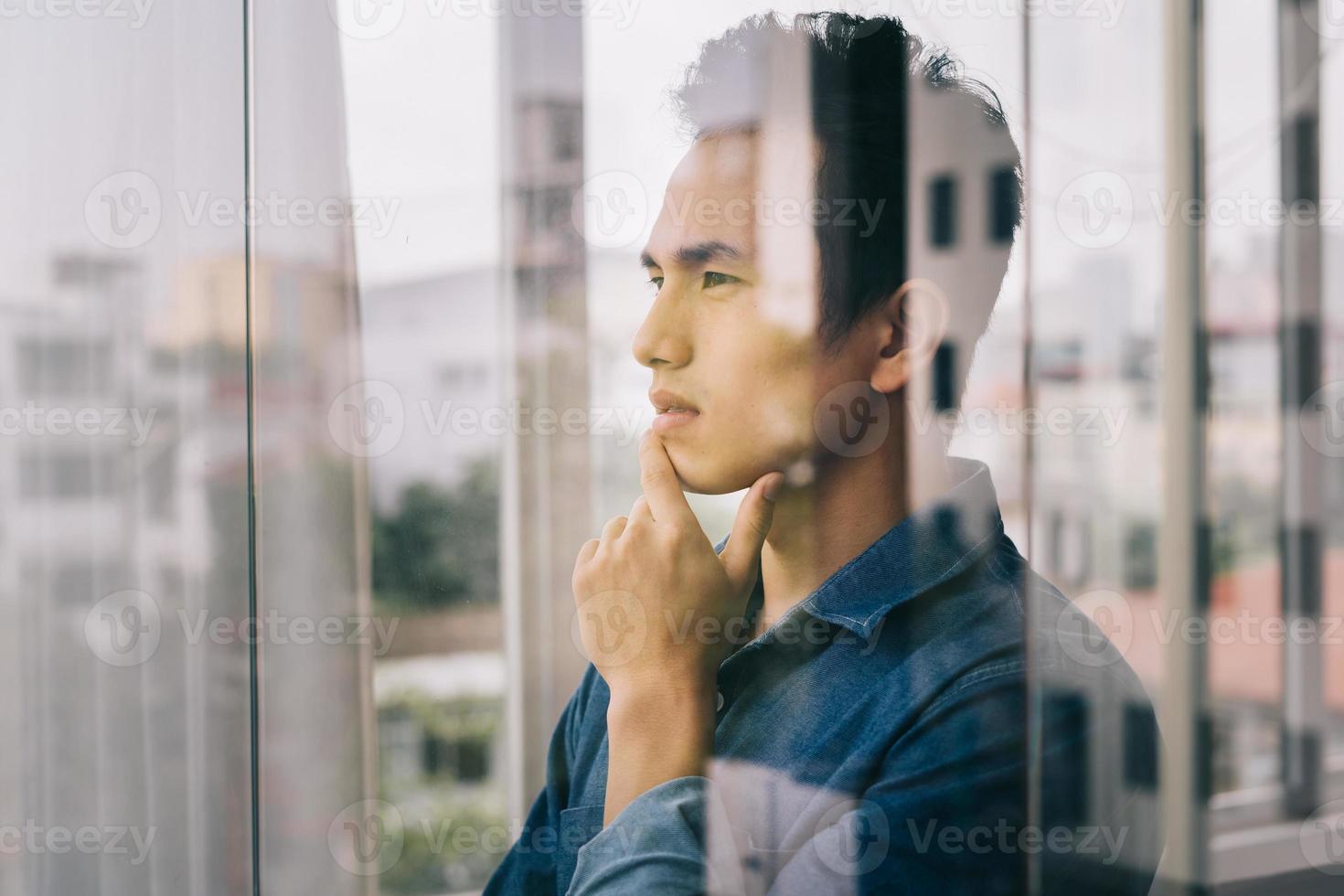 den asiatiska mannen funderade vid glasdörren foto