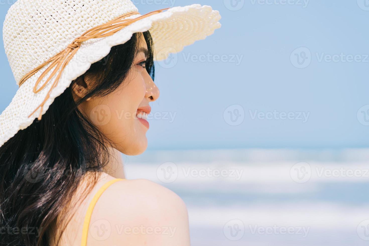 ung asiatisk kvinna som tycker om sommarsemester på stranden foto