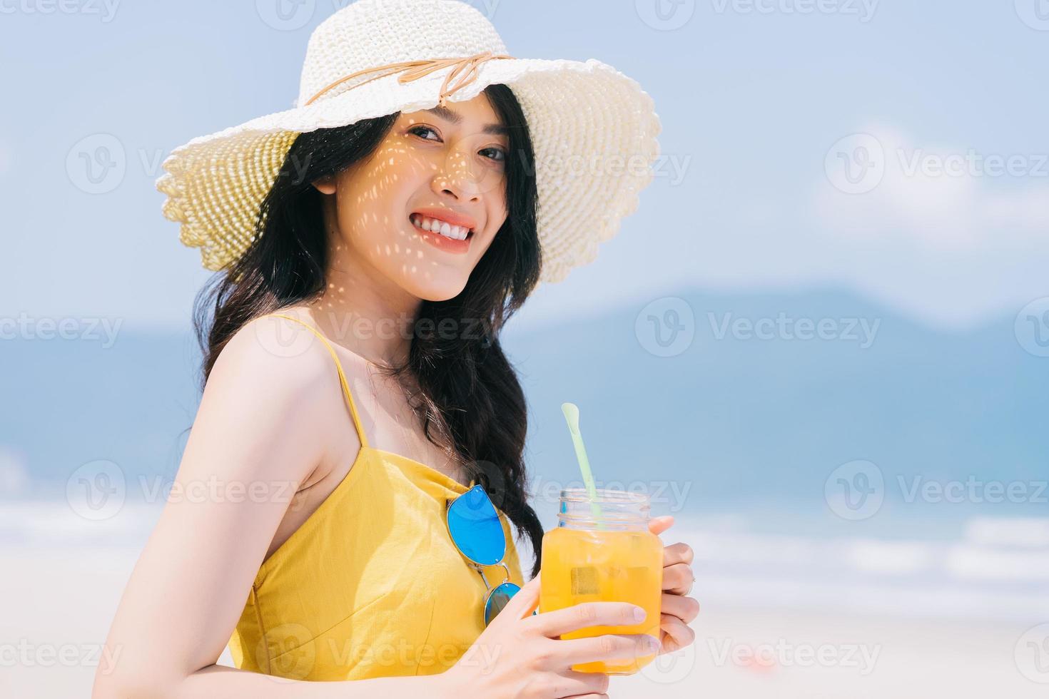 ung asiatisk kvinna som tycker om sommarsemester på stranden foto