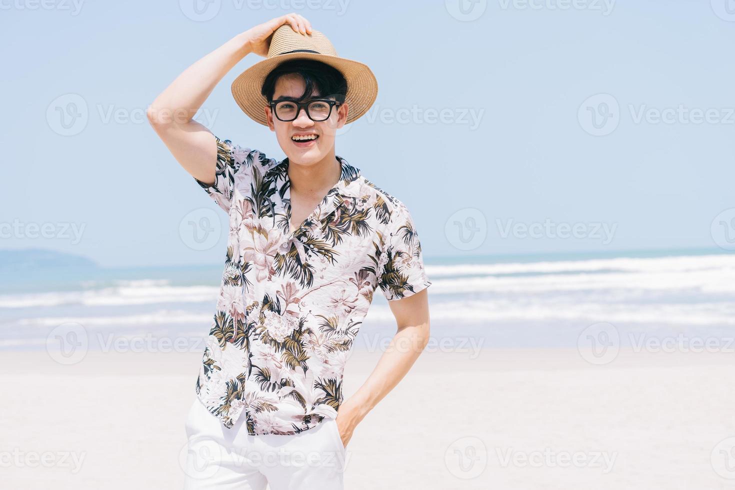 ung asiatisk man som går på stranden foto
