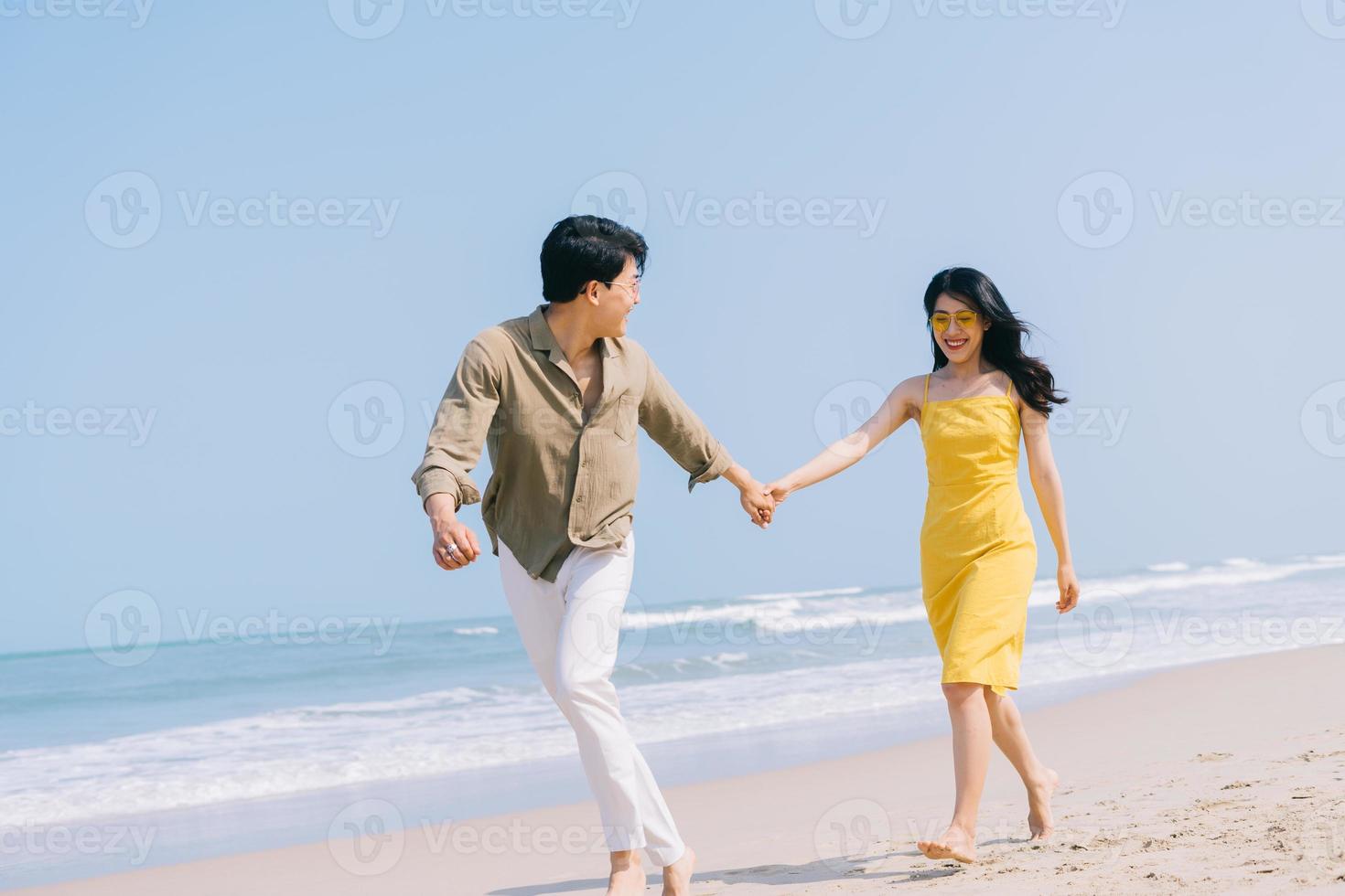 unga asiatiska par njuter av sommarsemester på stranden foto