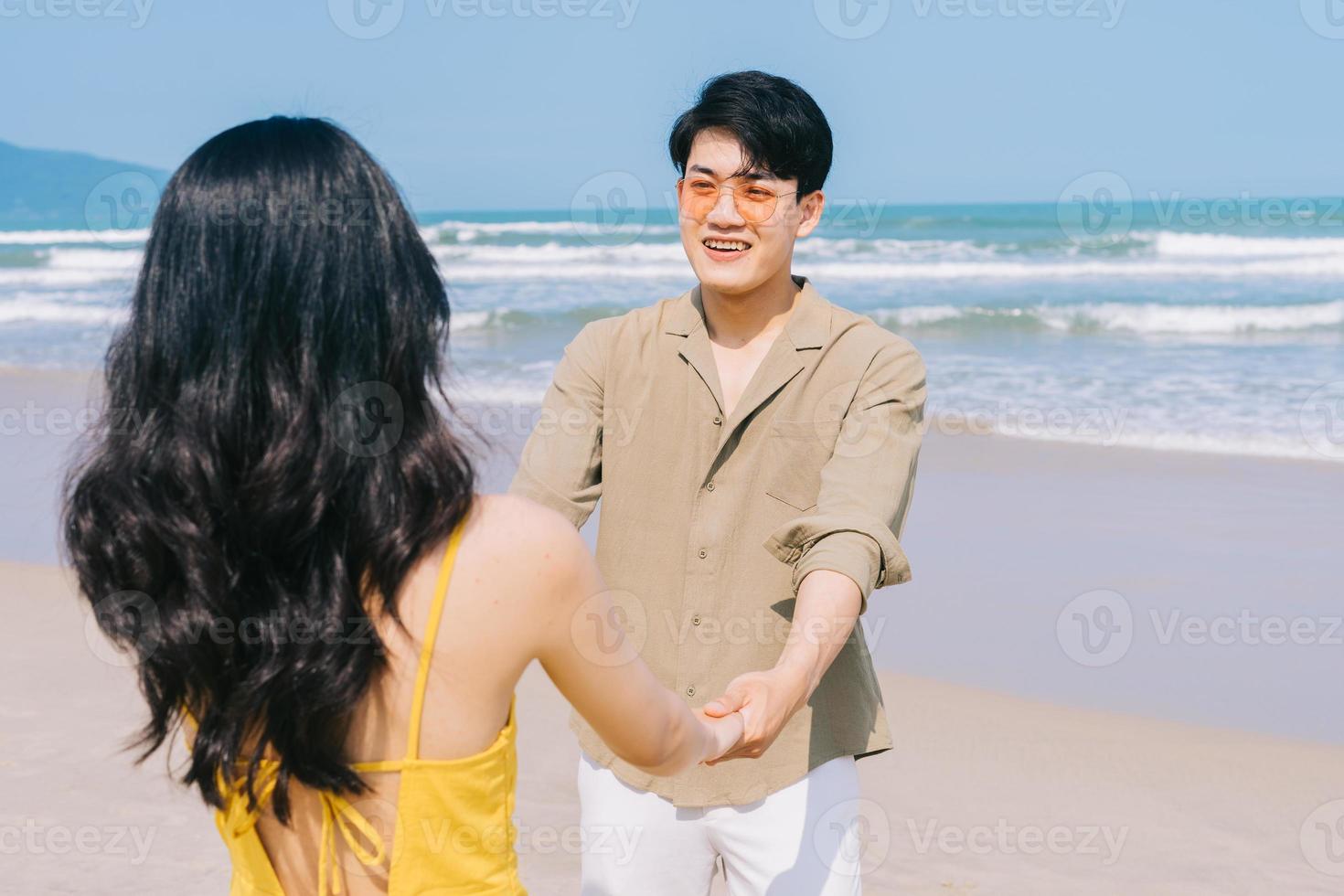 unga asiatiska par njuter av sommarsemester på stranden foto