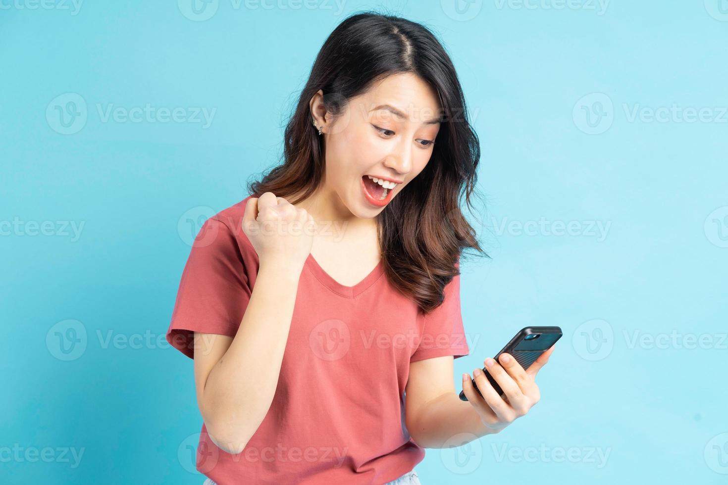 den vackra asiatiska kvinnan tittar på sin telefon och visar ett triumferande uttryck foto
