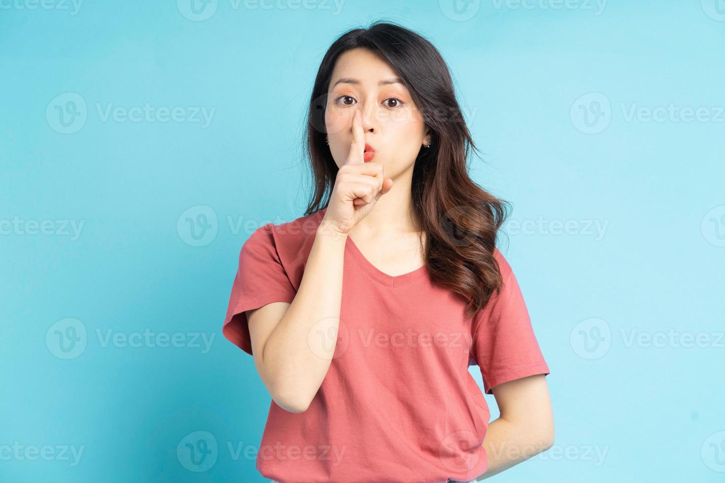 den vackra asiatiska kvinnan täckte munnen med ett finger för att beteckna tystnaden foto