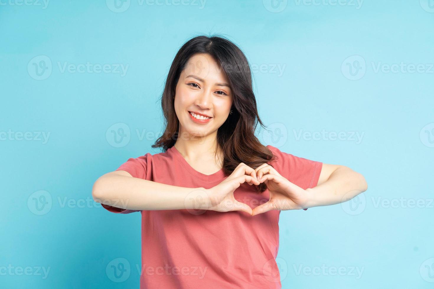 vacker asiatisk kvinna som formar hjärta med handen foto