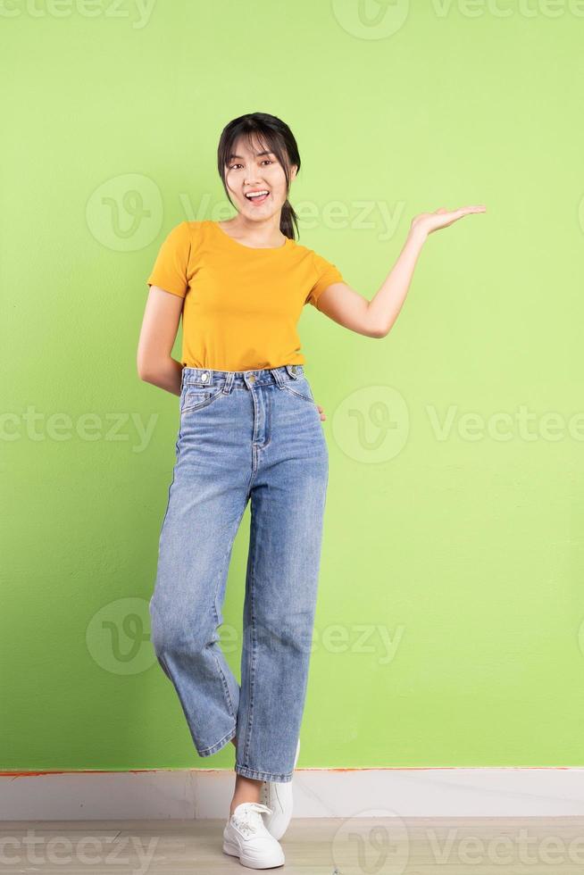 helkroppsporträtt av ung asiatisk tjej på grön bakgrund foto