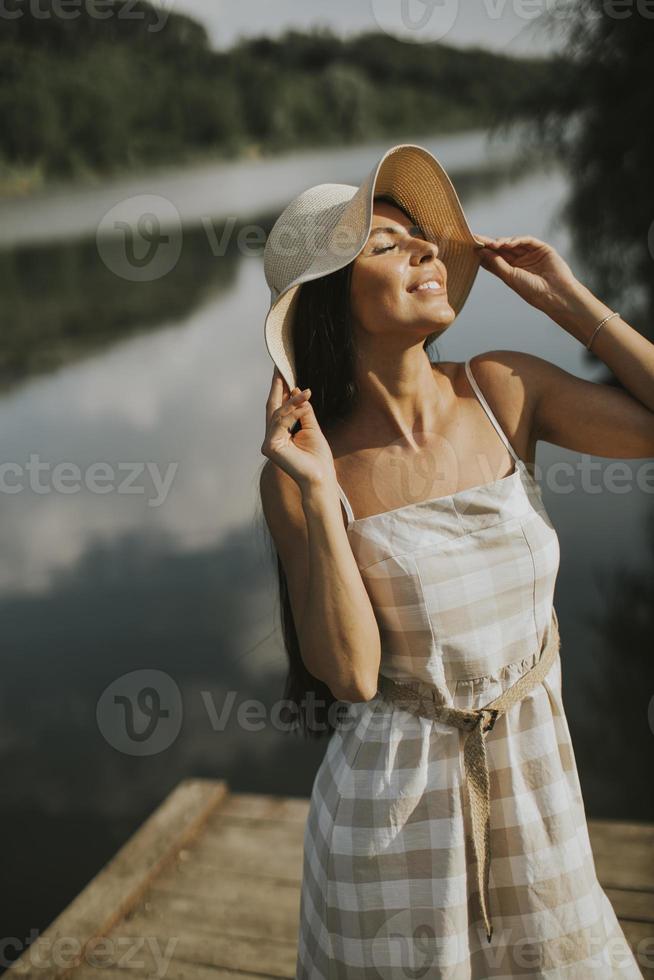 avkopplande ung kvinna som står på träbrygga vid sjön foto