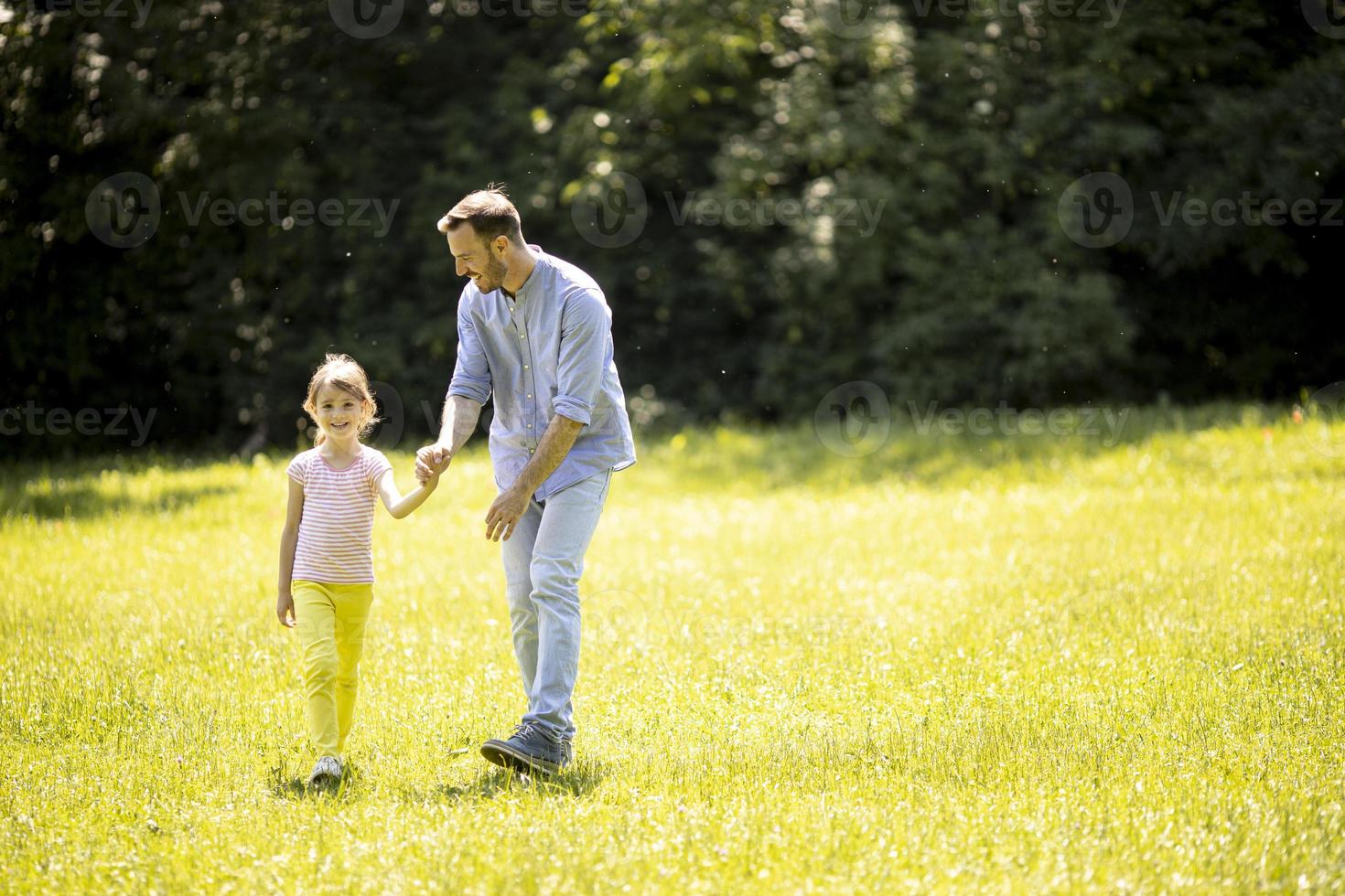 far med dotter som har kul på gräset i parken foto