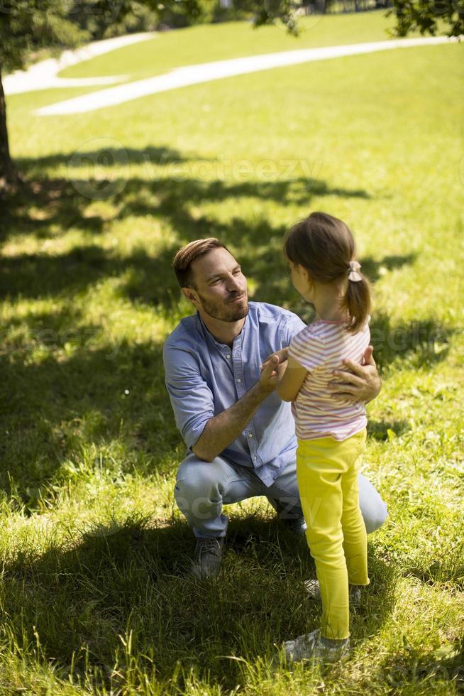 far med dotter som har kul på gräset i parken foto
