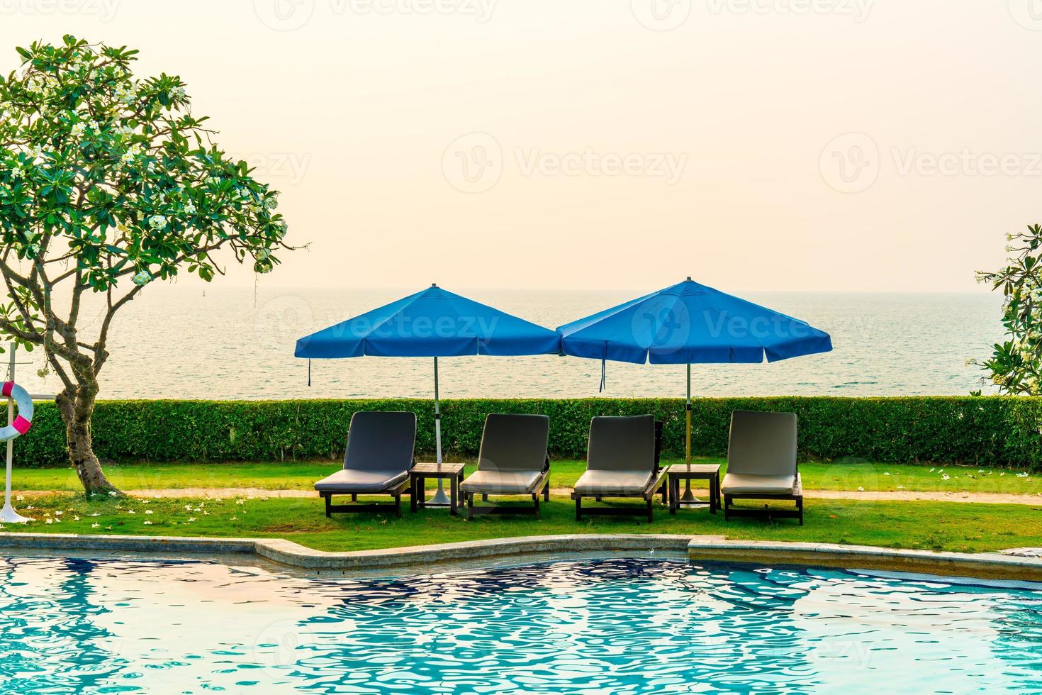 solstolar eller poolbäddar med parasoller runt poolen vid solnedgången foto